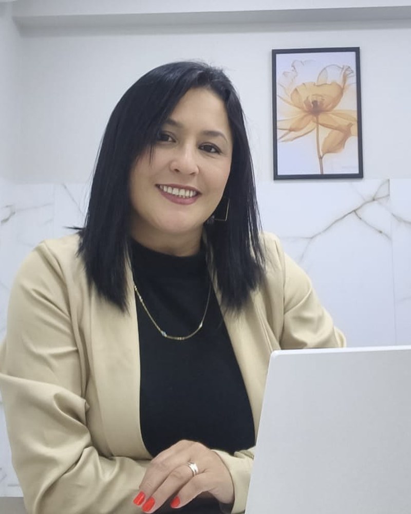Ester Miranda, psicóloga, sorrindo em seu consultório